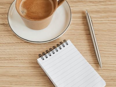 A notebook with a pen on a wooden table.